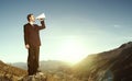 Businessman Shouting on the Top of the Mountain Concept