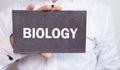 Businessman showing Biology word on cardboard.