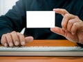 Businessman showing blank white plain namecard while working with keyboard computer on wooden table. Mockup business name card, Royalty Free Stock Photo