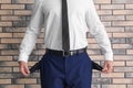 Businessman showing empty pockets near brick wall Royalty Free Stock Photo