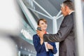 Businessman showing his electronic ticket on smartphone to passenger service agent in airport