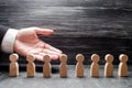 Businessman showing his hand to the wooden figures of people, workers. Hiring workers, human resources, headhunters.