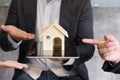Businessman showing house model on digital tablet. Realtor offer