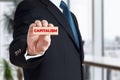 Businessman shows a wooden block with the word capitalism. Global corporate capitalism