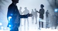 Businessman silhouette in formal suit holds out his hand for a handshake. Corporate culture concept. collegues are on background.