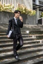 A businessman is sipping coffee while walking down the stairs in front of the building Royalty Free Stock Photo