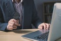 Businessman sit at office in suit holding magnifying glass and computer laptop. Royalty Free Stock Photo