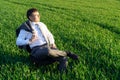 Businessman sits in an office chair in a field and rests, freelance and business concept, green grass and blue sky as background Royalty Free Stock Photo