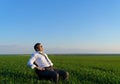 Businessman sits in an office chair in a field and rests, freelance and business concept, green grass and blue sky as background Royalty Free Stock Photo