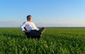 Businessman sits in an office chair in a field and rests, freelance and business concept, green grass and blue sky as background Royalty Free Stock Photo