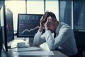 Businessman sits at a table with his head in his hands. Negative emotions due to falling stock prices in the market