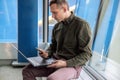 Businessman sitting at the airport working on a laptop and looking at the smartphone. Royalty Free Stock Photo