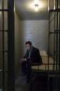 Businessman Sitting On Bed In Prison