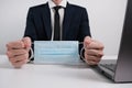 Businessman Sitting Behind a Table with Medical Mask Hands Bound Like Handcuffs