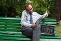 Businessman sitting on bench with mobile phone and tablet. Royalty Free Stock Photo