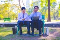 Businessman,They are sitting on bench in park.He is play notebook and search internet.A