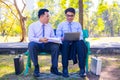 Businessman,They are sitting on bench in park.He is play notebook and search internet.A