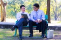 Businessman,They are sitting on bench in park.He is play notebook and search internet.A