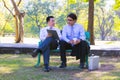 Businessman,They are sitting on bench in park.He is play notebook and search internet.A