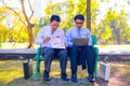 Businessman,They are sitting on bench in park.He is play notebook and search internet.A