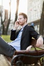 Businessman sitting on a bench and talking on the phone on a s