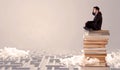 Businessman sitting on books in labirynth