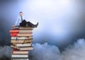 Businessman sitting on Books stacked by atmospheric clouds Royalty Free Stock Photo