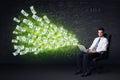 Businessman sitting in chair holding laptop with dollar bills co Royalty Free Stock Photo