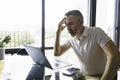 Businessman sitting at desk in bright office using laptop with sad attitude Royalty Free Stock Photo