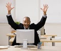 Businessman sitting at desk cheering