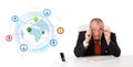 Businessman sitting at desk with a globe and social icons Royalty Free Stock Photo