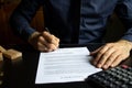 Businessman sitting at desk in home office signing contract with shallow focus on signature. Concluding a contract in a secure Royalty Free Stock Photo