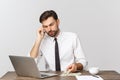 Businessman sitting at desk in office and talking on mobile phone Royalty Free Stock Photo