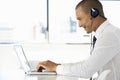 Businessman Sitting At Desk In Office Using Laptop Wearing Headset Royalty Free Stock Photo