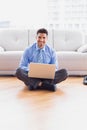 Businessman sitting on floor using his laptop smiling at camera Royalty Free Stock Photo