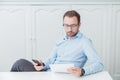 Businessman sitting at his desk, looking at paper document and h