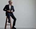 Businessman sitting and holding his jacket`s button looking sideways Royalty Free Stock Photo