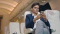 Businessman sitting inside plane watching video on mobile phone during his business trip Royalty Free Stock Photo