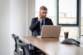 Businessman sitting in a modern office and using mobile phone and laptop for work Royalty Free Stock Photo