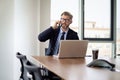 Businessman sitting in a modern office and using mobile phone and laptop for work Royalty Free Stock Photo