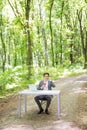 Businessman sitting at the office desk with laptop computer and cup of coffee talking mobile phone on in green forest park. Busine Royalty Free Stock Photo