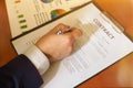 Businessman sitting at office desk signing a contract with shallow focus on signature Royalty Free Stock Photo