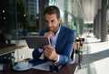 Businessman sitting outside at a cafe table using a tablet Royalty Free Stock Photo