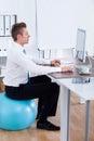 Businessman Sitting On Pilates Ball And Using Computer Royalty Free Stock Photo