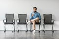 Businessman sitting in recruitment waiting room for interview with HR, using cellphone, full length Royalty Free Stock Photo