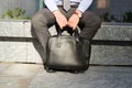 Businessman sitting / resting after working day and holding a leather briefcase in his hand. Royalty Free Stock Photo