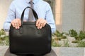 Businessman sitting / resting after working day and holding a leather briefcase in his hand