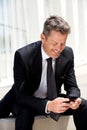 Businessman sitting and smiling holding mobile phone Royalty Free Stock Photo