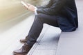 The businessman sitting on stairs and using smartphone