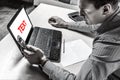 Businessman sitting at the table with a laptop in the office and looking tensely into the phone and screen. Mockup, place for text Royalty Free Stock Photo